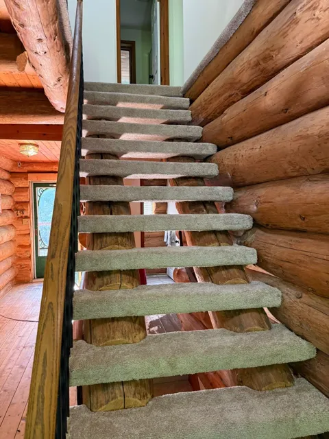Close-up of carpet-wrapped half-log treads on an open-riser staircase
